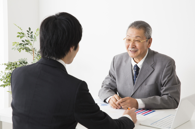 デスクで年配の男性に転職の相談をする男性